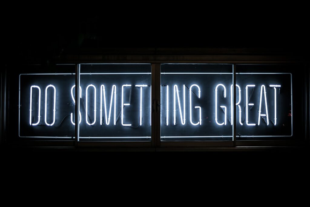A glowing neon sign against a dark background reads "DO SOMETHING GREAT" in bold, white letters.